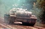 304px-A_left_rear_view_of_a_Soviet-built_T-62A_main_battle_tank_underway._Mounted_at_the_rear_of_the_hull_are_two_drum_fuel_tanks_and_an_unditching_beam.JPG